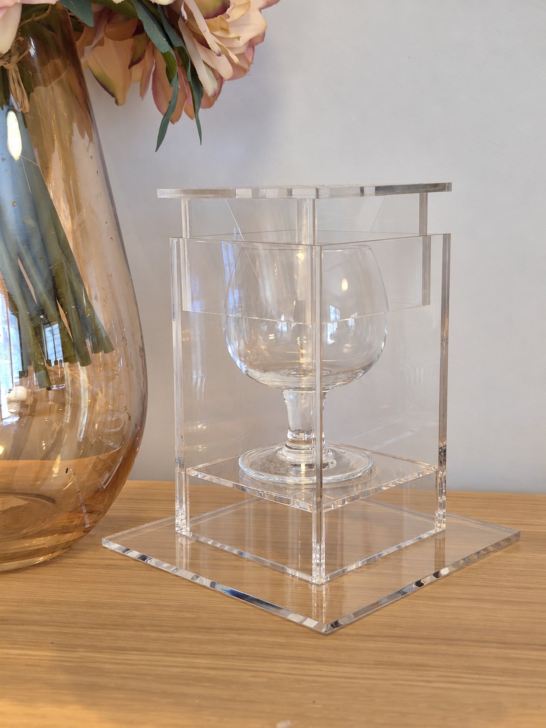 Angled view of the plain transparent acrylic case holding the clear glass ceremony cup